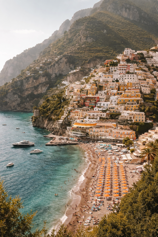 Amalfikust Italië met kleurrijke huizen, turquoise zee en strand met oranje parasols als luxe mediterrane wanddecoratie.