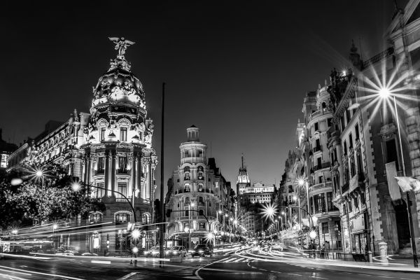Zwart-wit foto van Madrid bij nacht met verlichte historische gebouwen en lichtsporen van verkeer op de Gran Vía.