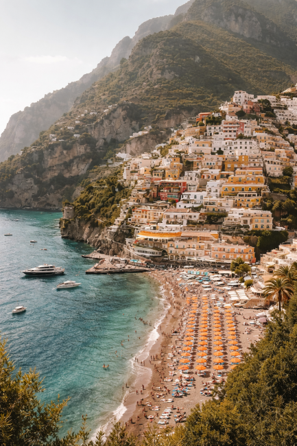 Amalfikust Italië met kleurrijke huizen, turquoise zee en strand met oranje parasols als luxe mediterrane wanddecoratie.